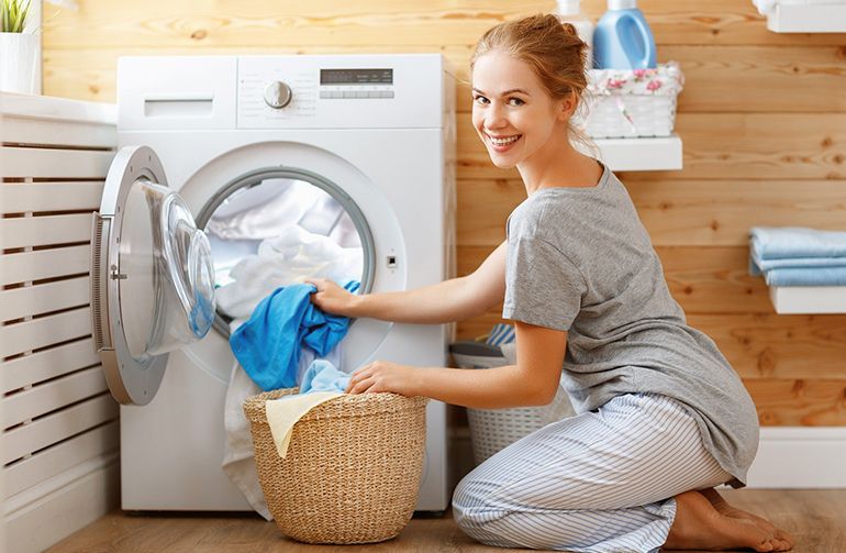 mujer sacando ropa de la lavadora