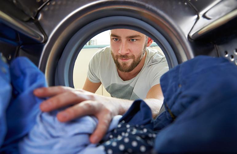 hombre metiendo ropa en una lavadora las franquicias más rentables
