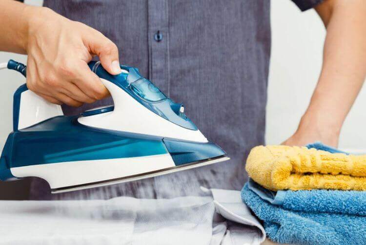 hombre planchando ropa en servicios de lavandería industrial
